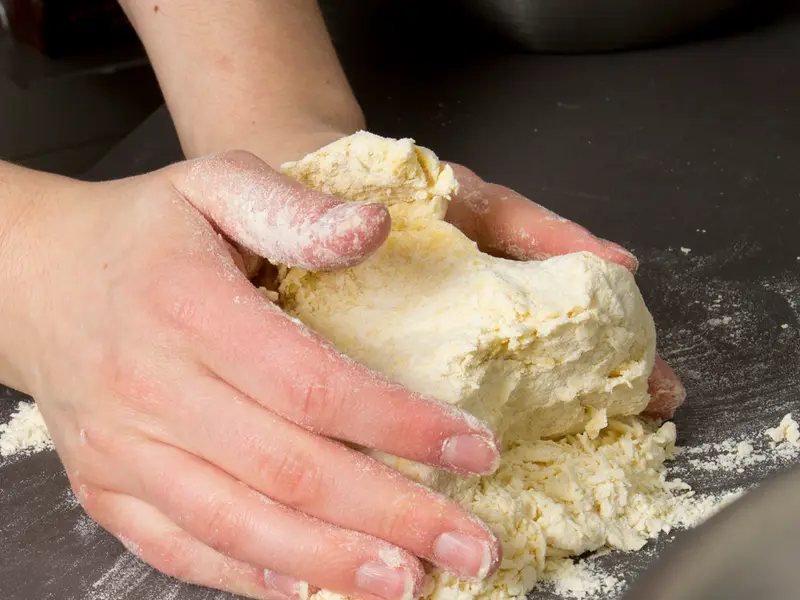 Des mains travaillant une pâte sur un plan de travail (photo d’illustration)