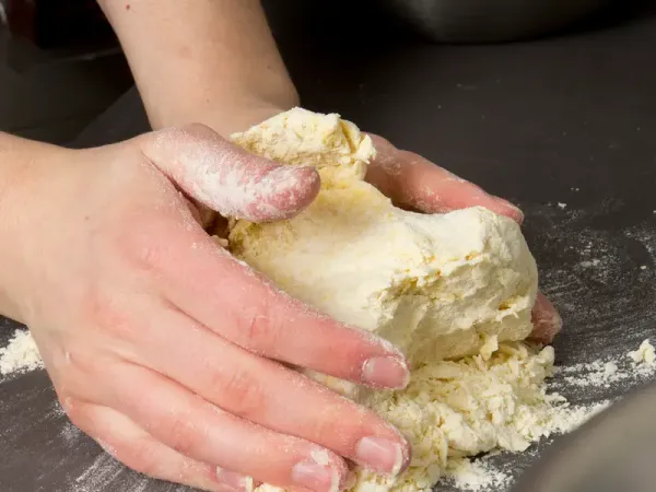 Des mains travaillant une pâte sur un plan de travail (photo d’illustration)